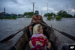 Vecinos recorren una calle inundada en un bote de madera en Guanimar, provincia de Artemisa, donde varias localidades quedaron bajo el agua tras el paso del huracán Helene, el miércoles 25 de septiembre de 2024. (Foto AP/Ramon Espinosa)