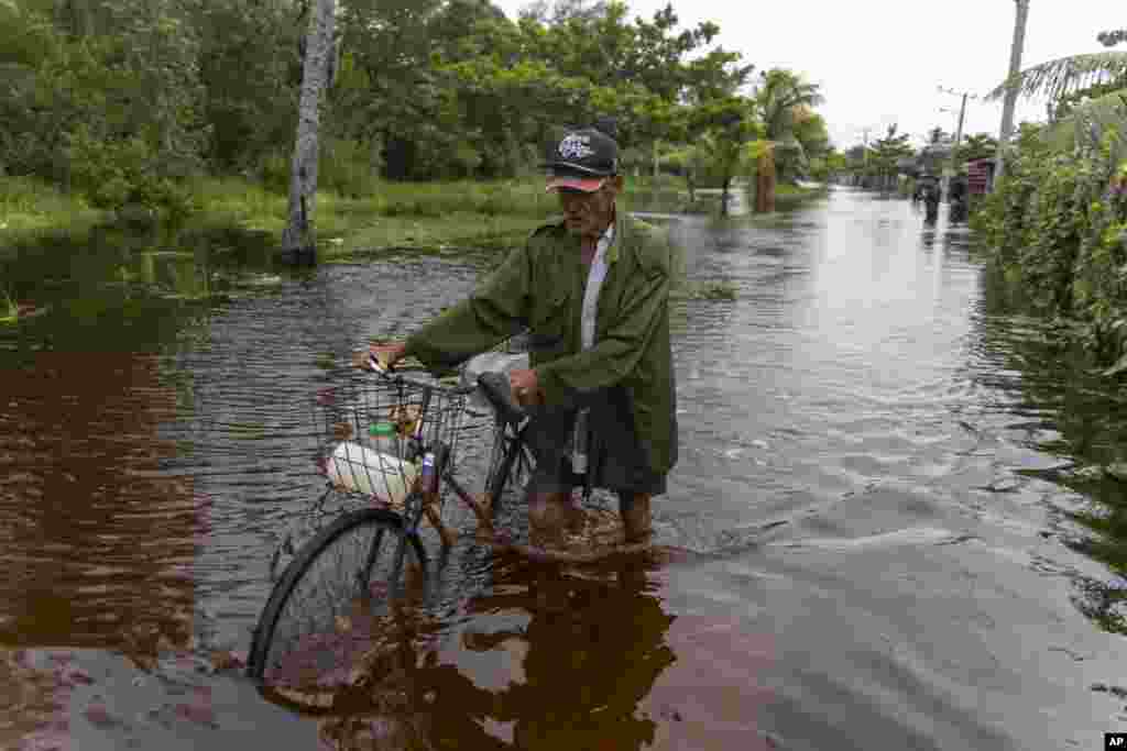 Un hombre empuja su bicicleta por una calle inundada después del paso del huracán Helene por Guanimar, provincia de Artemisa, Cuba, el miércoles 25 de septiembre de 2024. (Foto AP/Ramon Espinosa)